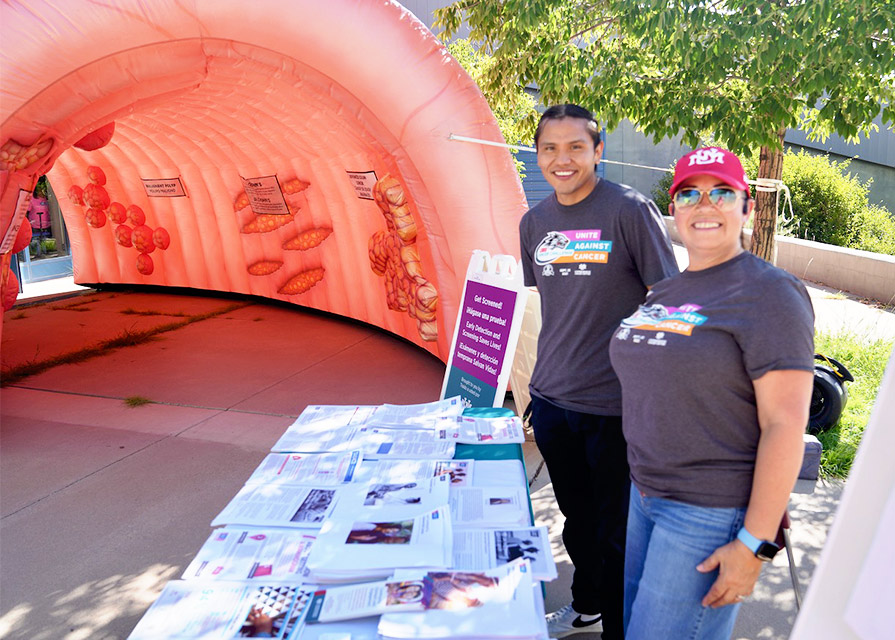 Two community engagement specialists pose with a giant inflatable colon
